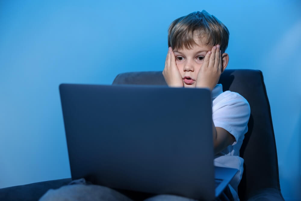 Cyber,Danger.,Frightened,Little,Boy,Using,Laptop,On,Blue,Background
